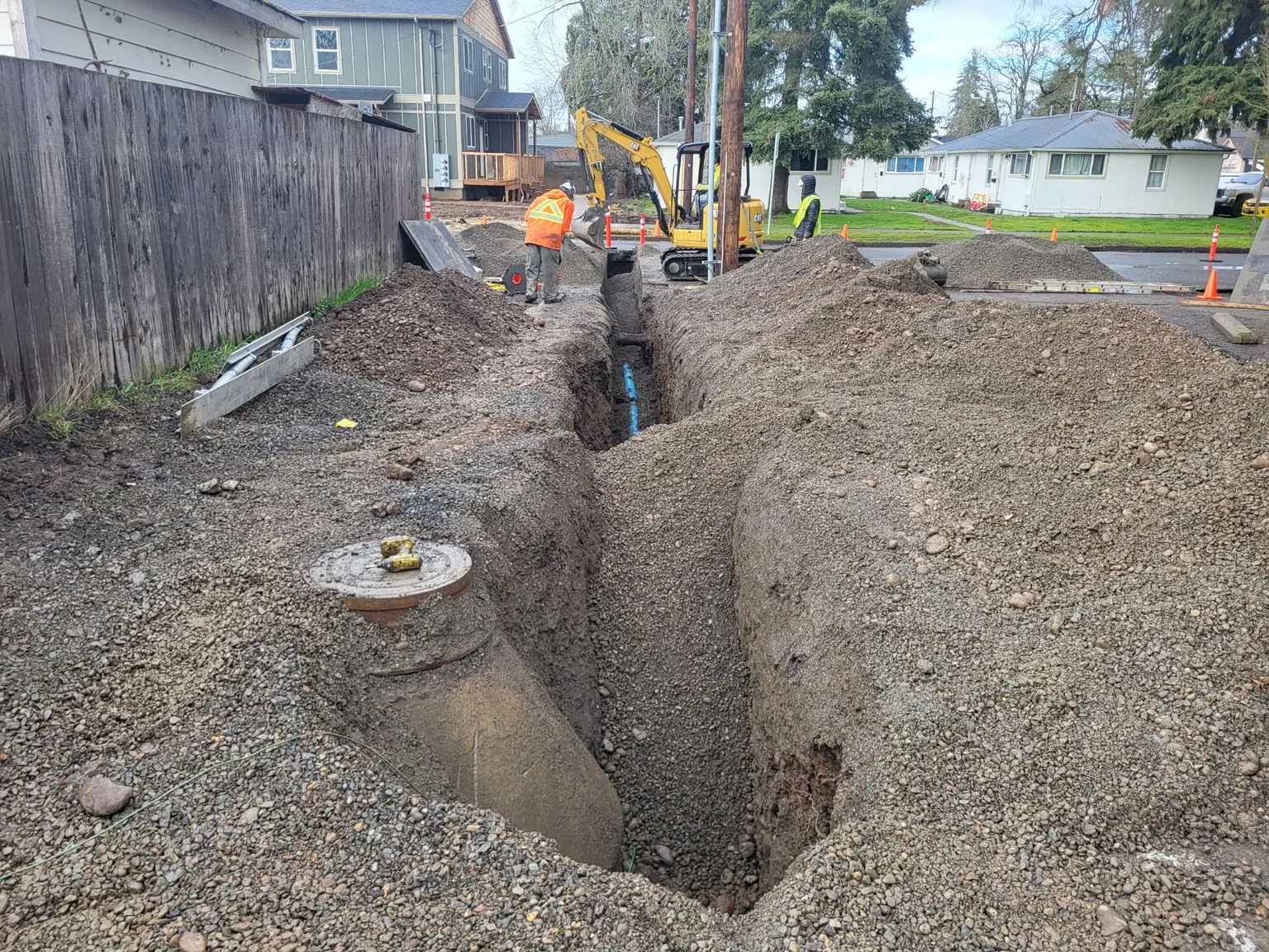 A deep trench beside a capped riser, the line exposed at the bottom