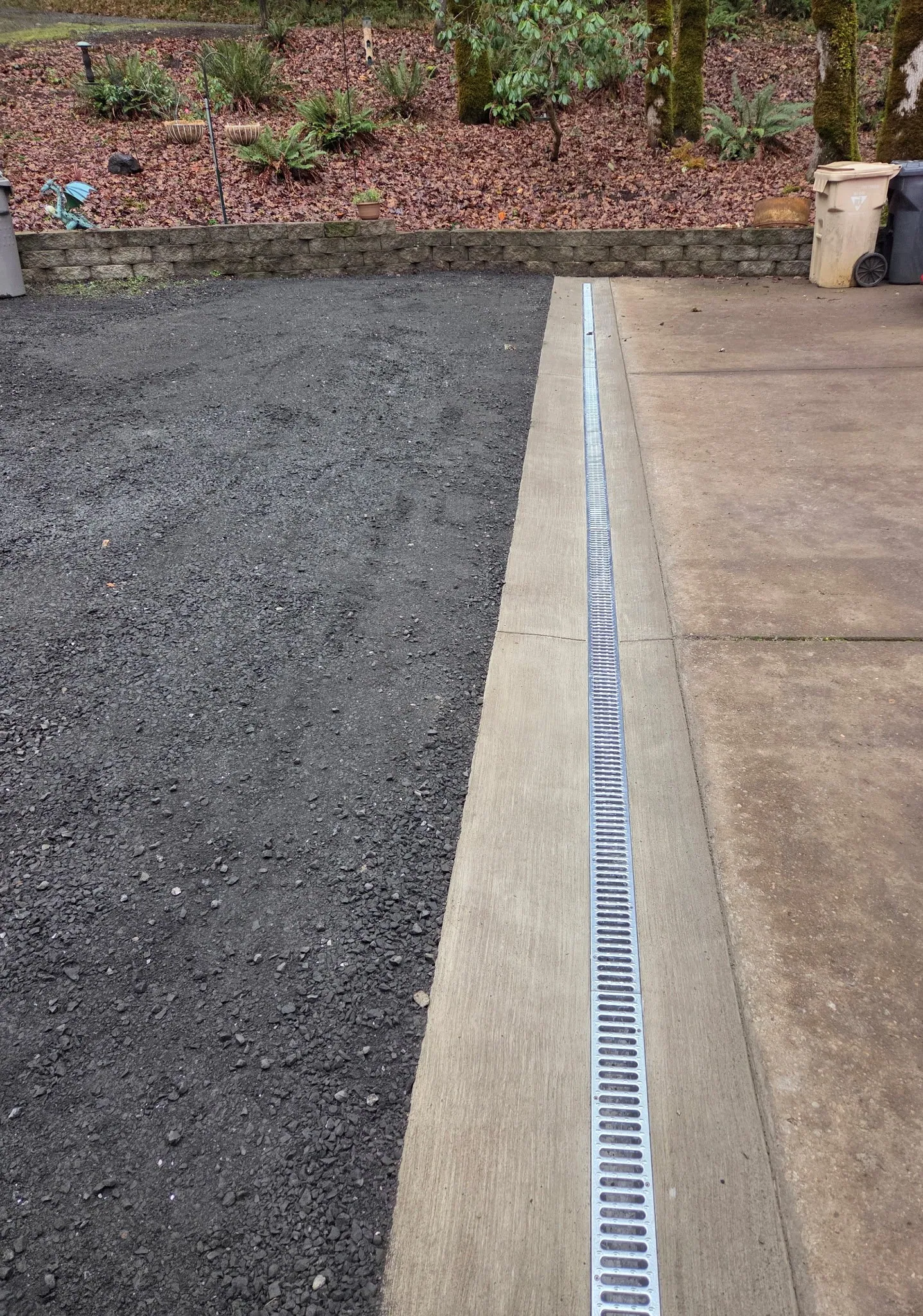 A trench drain set between new asphalt and a concrete walk