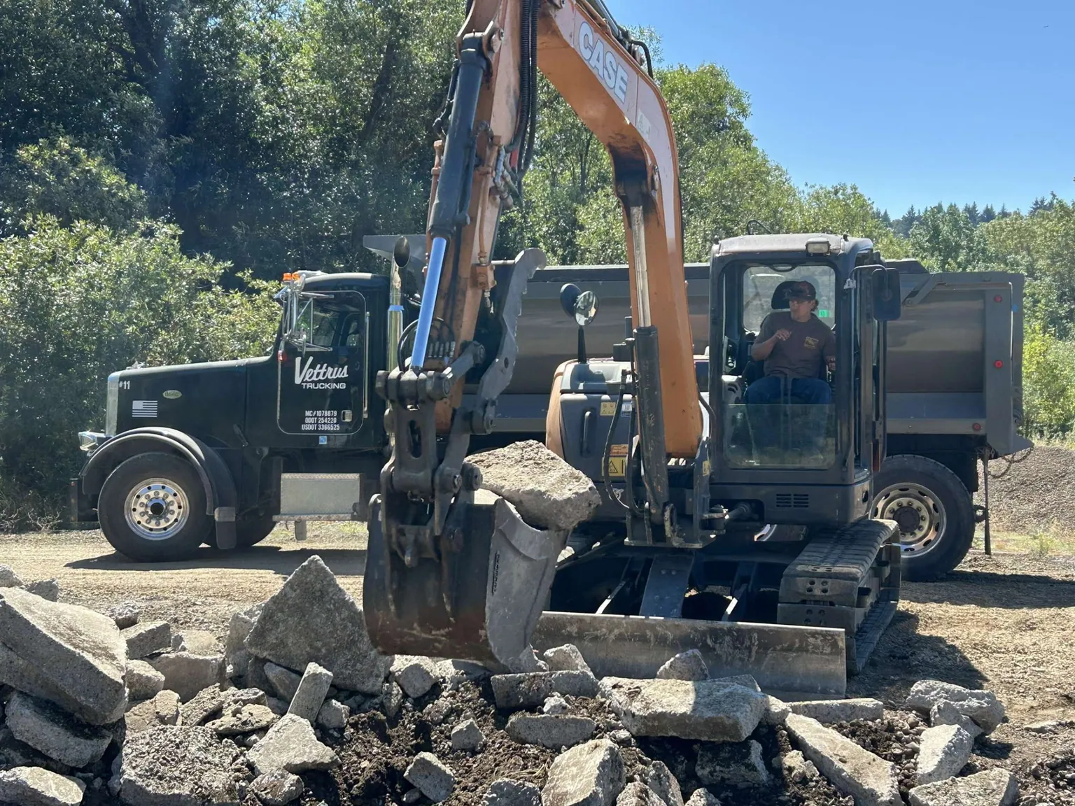 Excavator and dump truck hauling off old concrete