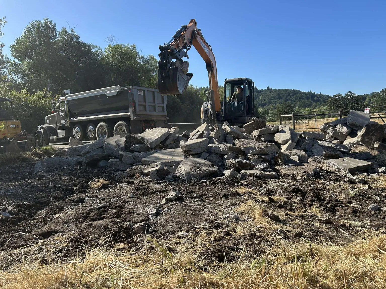 Excavator loading broken concrete into a dump truck