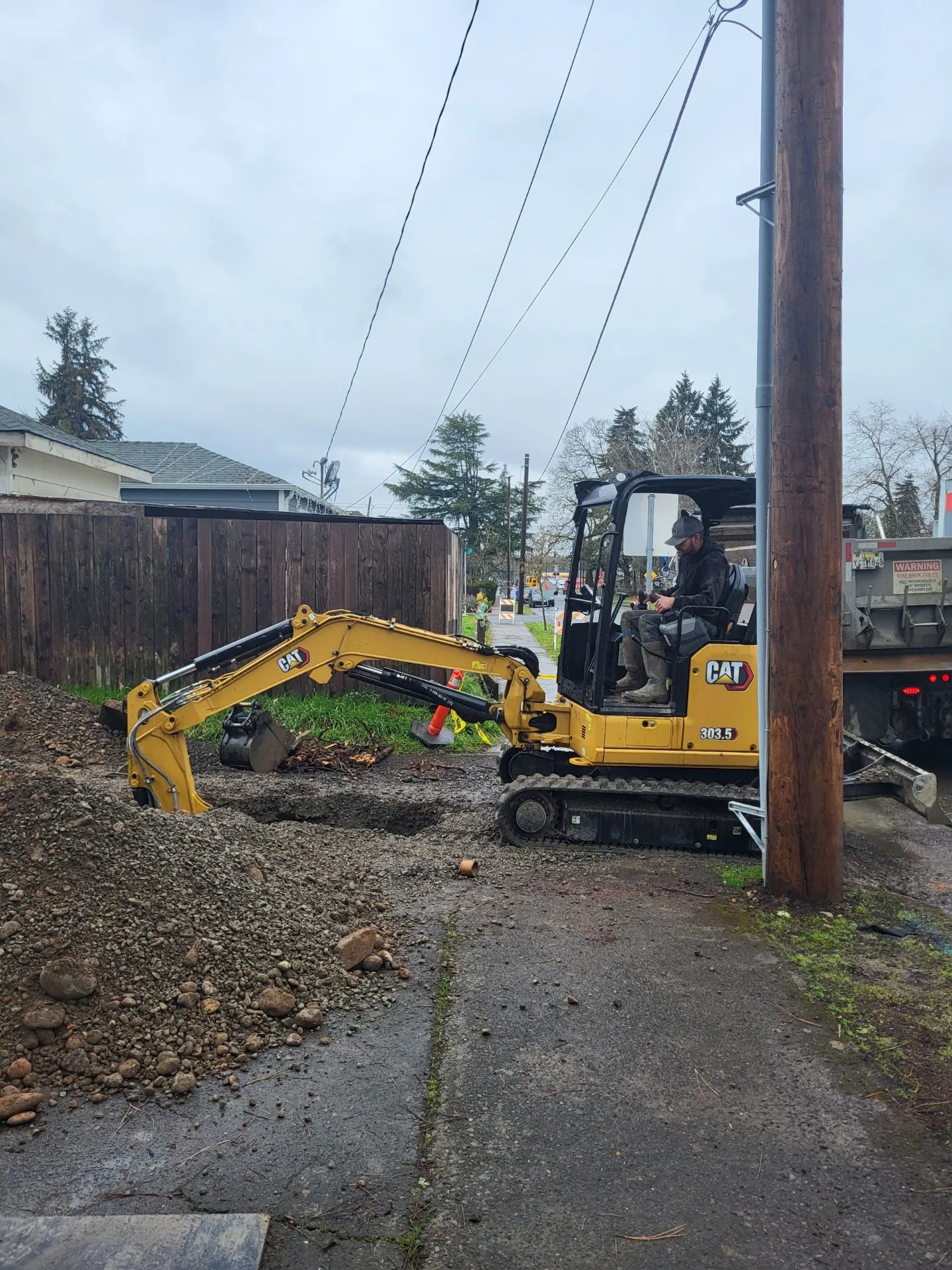 Mini excavator working along an alley behind houses