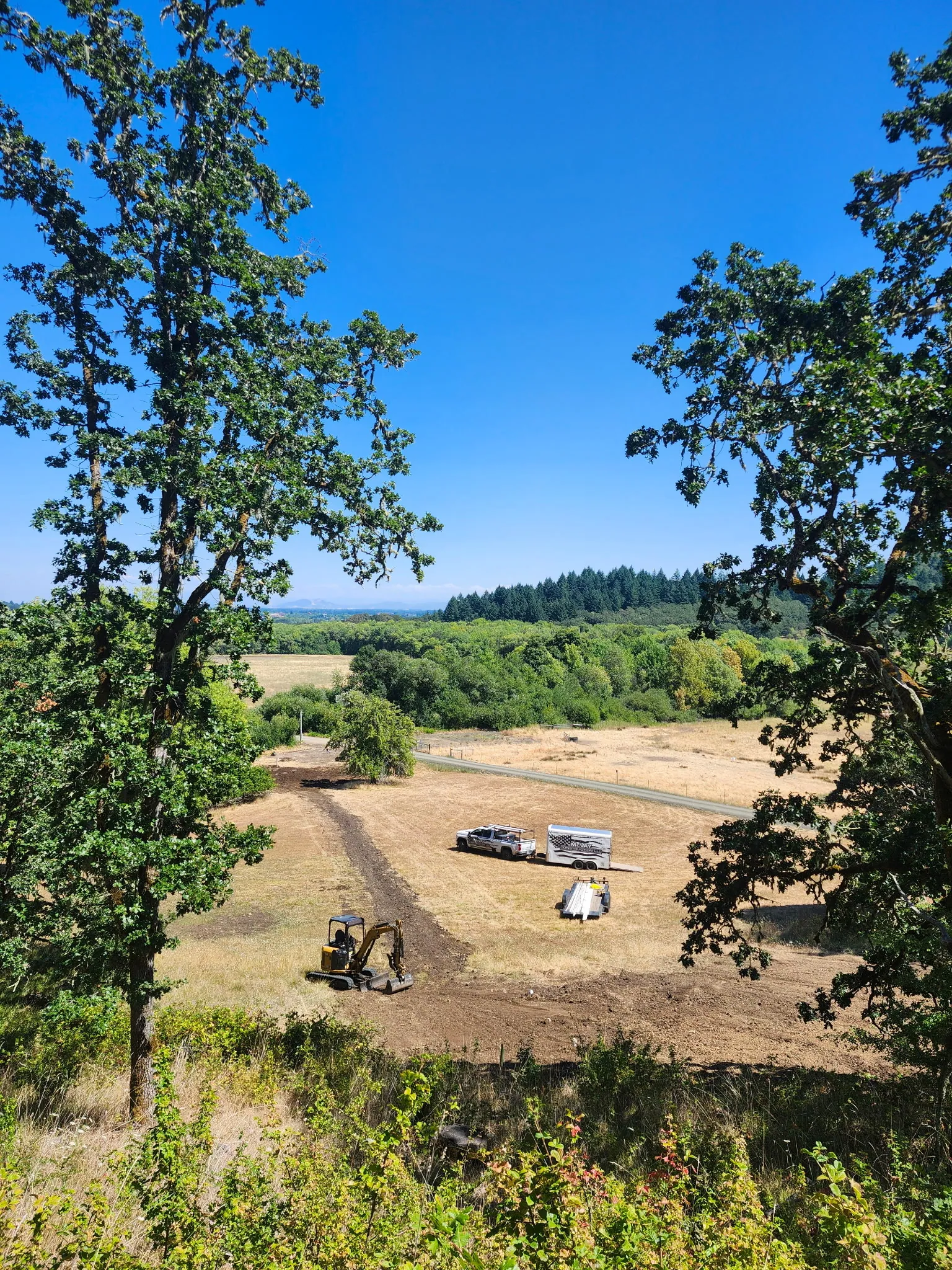 Looking down on a rural hillside lot during a long drain line job
